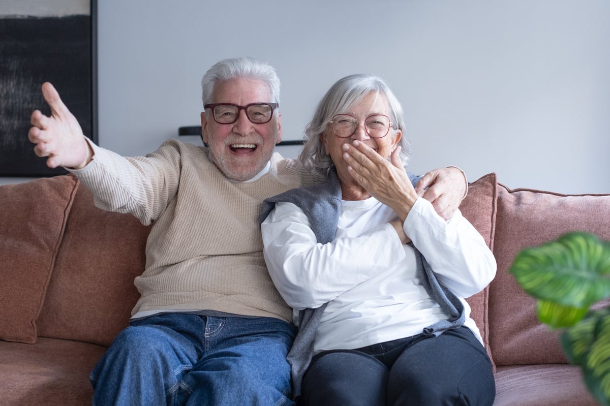 African American elderly couple laughing and embracing on a living room couch